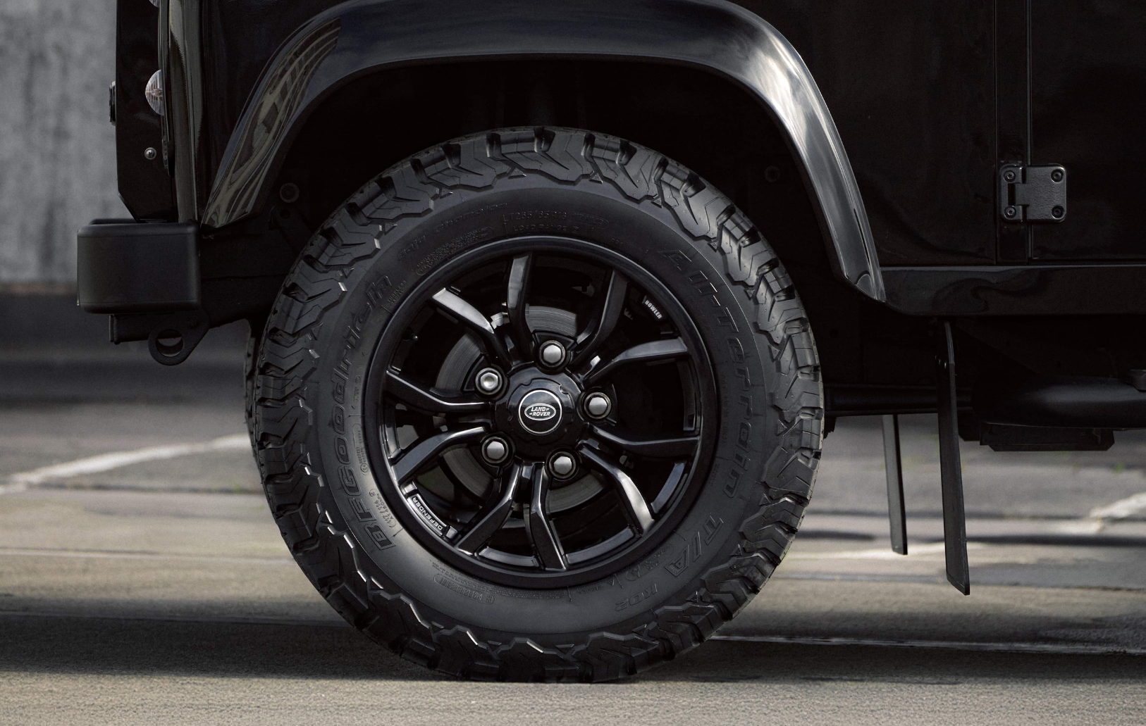 Rear off-road tire on a black Defender.