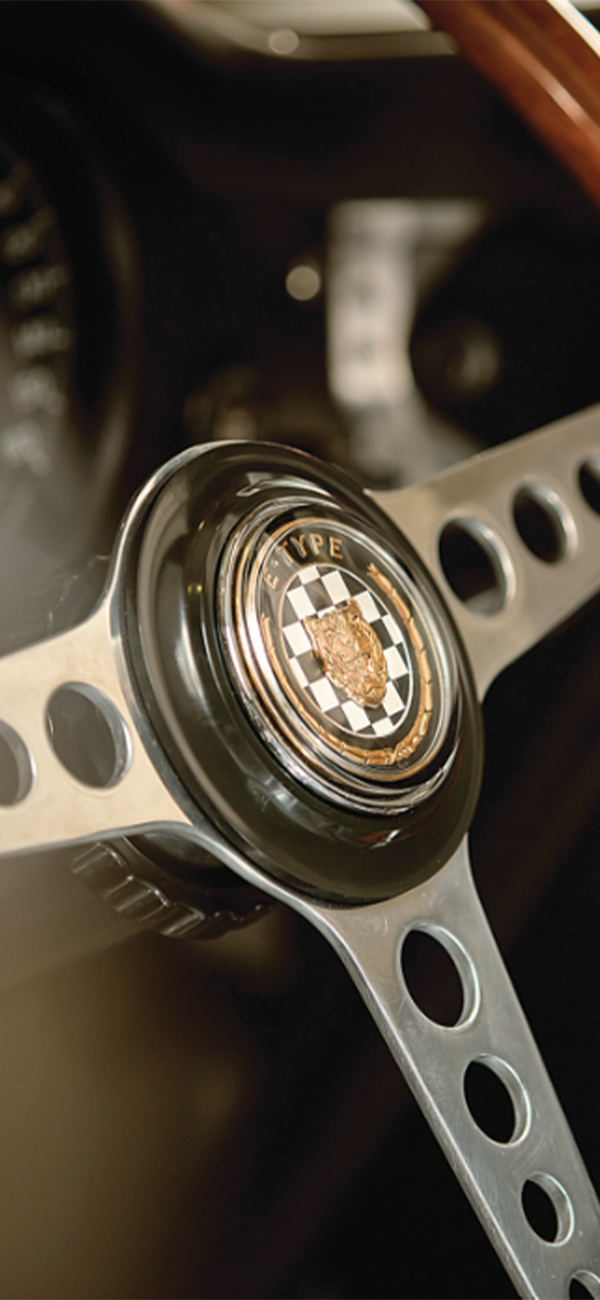 Classic car steering wheel with “E-TYPE” customised emblem.