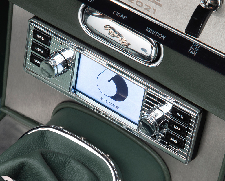 Jaguar E-Type centre console with control panel and display screen.