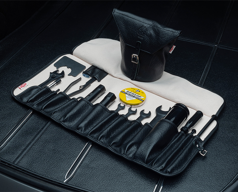 Classic car toolkit with wrenches, screwdrivers, and Dunlop gauge in black leather roll.
