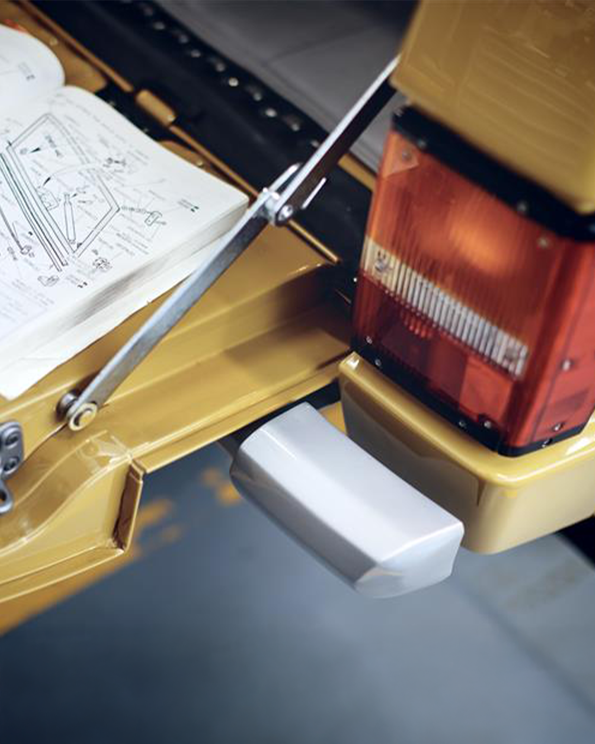 Open book with diagrammes on tailgate of yellow Range Rover, showing taillight and bumper.
