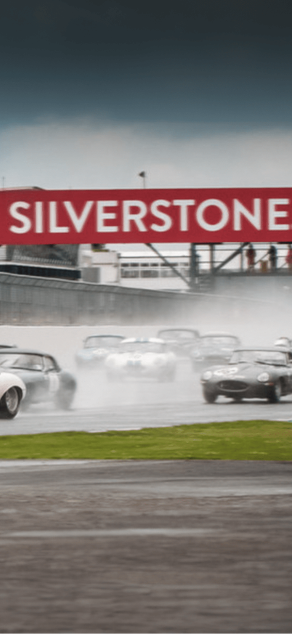 Classic race cars on wet track at Silverstone.