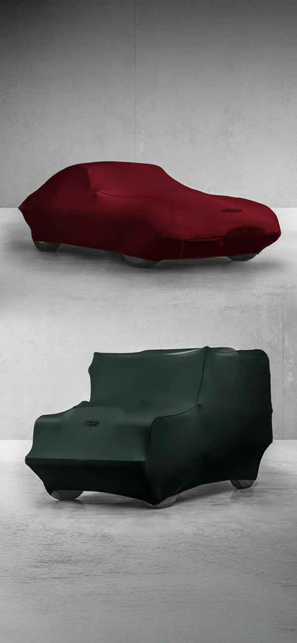 Classic Jaguar and Land Rover covered with fabric car cover in minimalist concrete room.