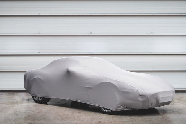 Covered Jaguar parked in front of closed metal garage door.