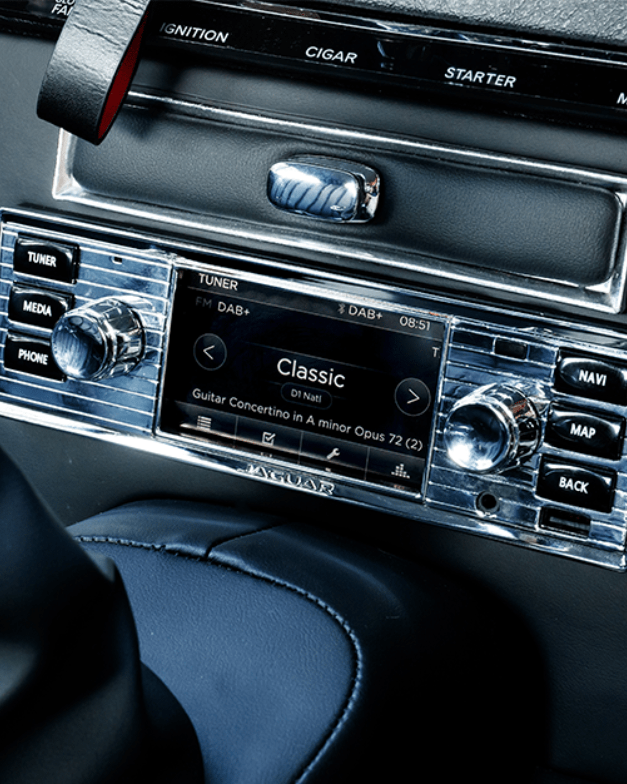 Car dashboard control panel with radio display showing classical music track and labeled buttons.