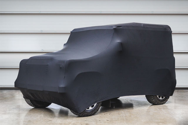 Covered Land Rover parked in front of closed metal garage door.